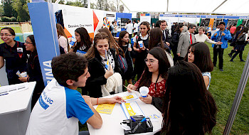 Foto de estudiantes haciendo consultas por carreras en feria.
