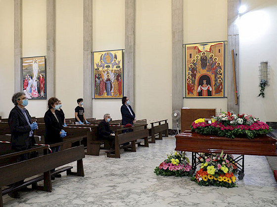 Foto de un funeral con pocas personas con mascarillas.