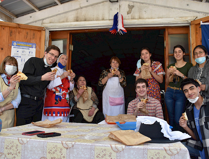 Personas en el comedor social comiendo empanadas