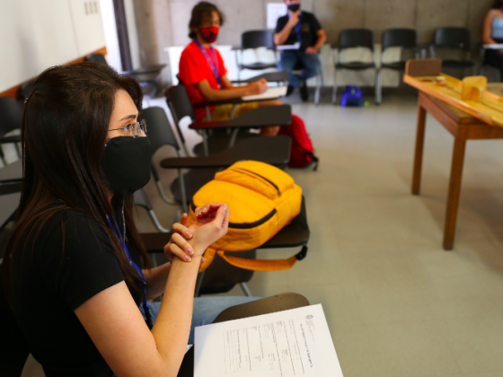 alumnos sentados en sillas dentro de una sala de clases, usando mascarilla