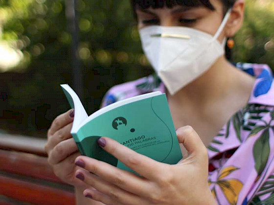 Imagen de veinteañera leyendo en un parque, con mascarilla, uno de los libros recopilatorios con cuentos breves del concurso Santiago en 100 palabras.