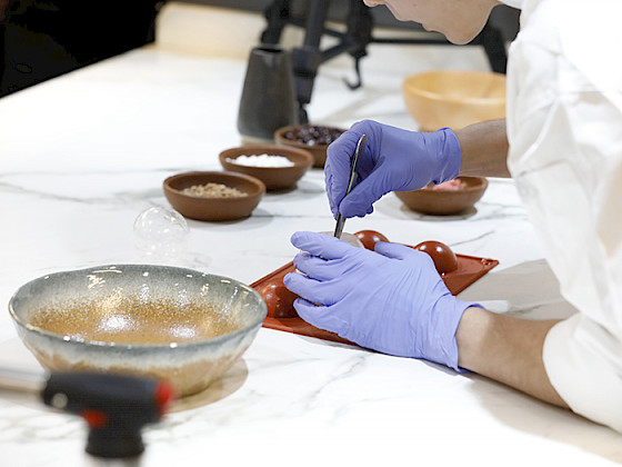 Una cocina hecha laboratorio donde aparece una mujer interviniendo alimentos.
