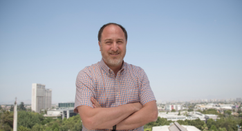 Roberto González, psicólogo UC, en la terraza del Centro de Innovación UC, y de fondo, el campus San Joaquín.