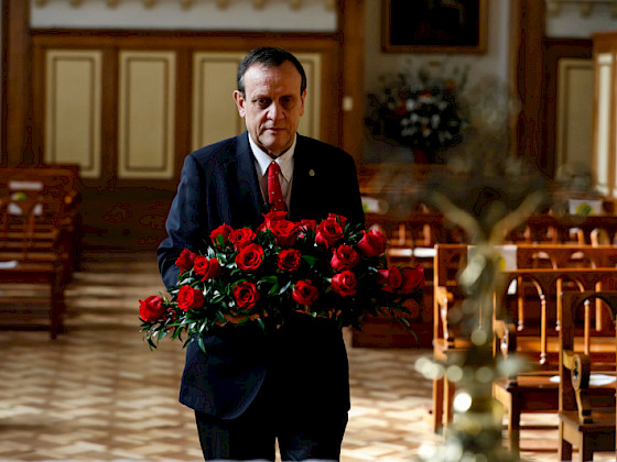 hombre dentro de una capilla llevando ramo de rosas rojas