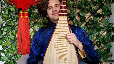 a man in a blue shirt holding a chinese musical instrument