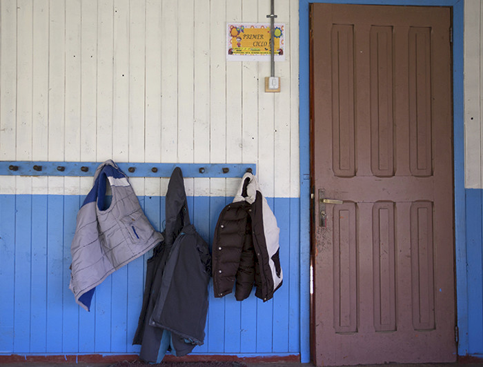 Tres parkas colgando en un perchero junto a la puerta de una escuela.