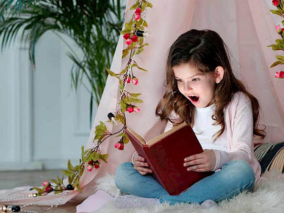 niña leyendo un libro, su rostro expresa alegría