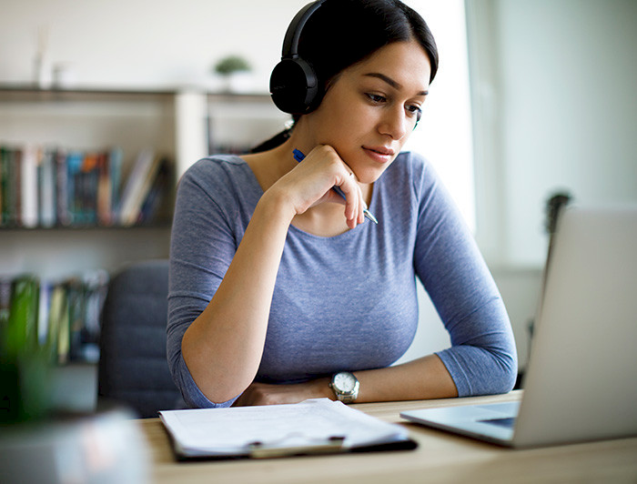 female student with headphones watching a computer