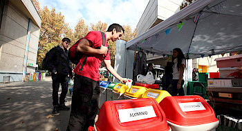 Personas botando residuos en contenedores para reciclar.