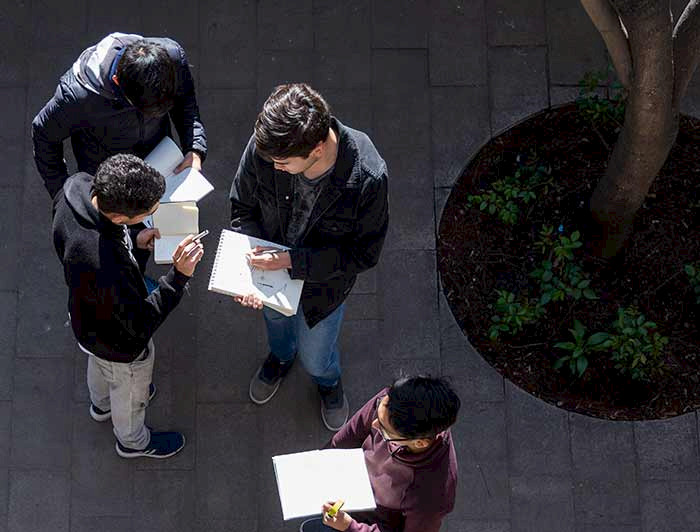 hombres jóvenes leyendo de pie en un patio