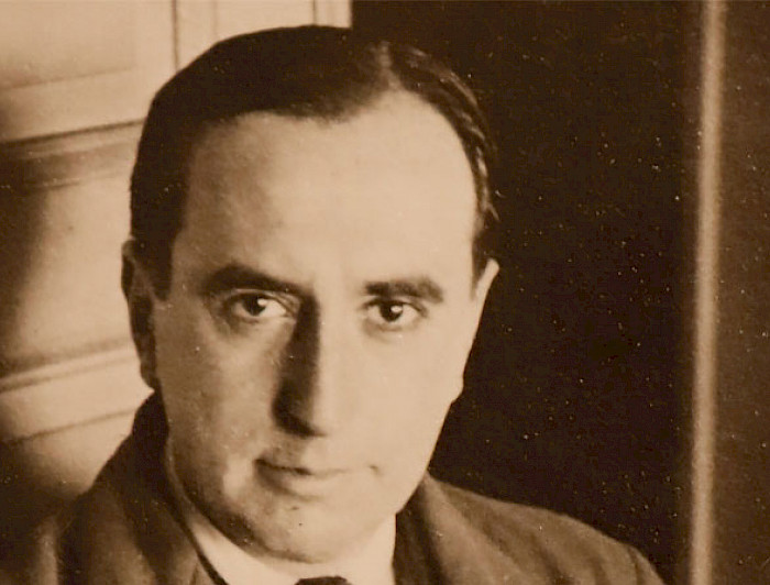 The Chilean writer and poet Vicente Huidobro is posing with a serious face. The photography is sepia.