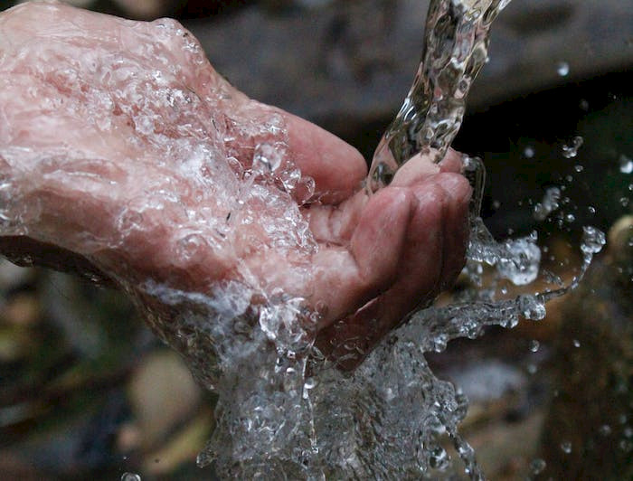 mano de persona mojándose con agua