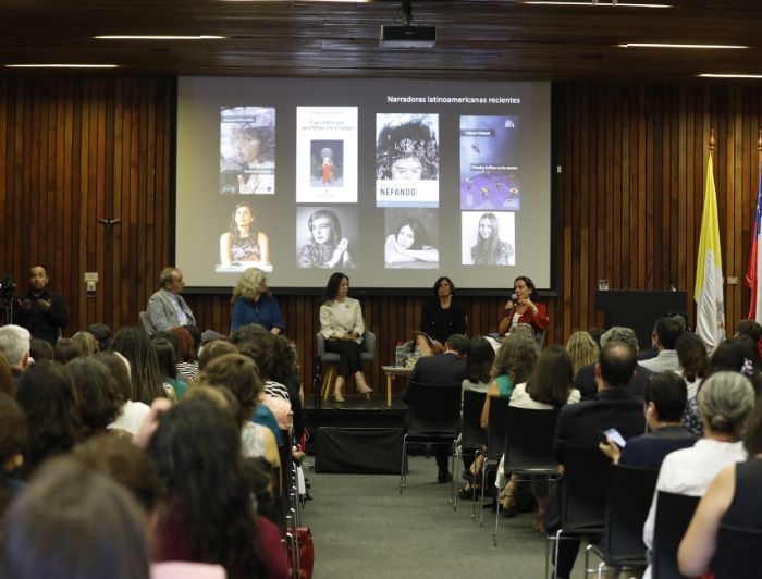 Un panel de cinco personas habla frente a un grupo de personas