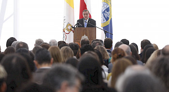 Rector Ignacio Sánchez dando su discurso en un podio frente al público.