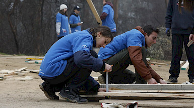 Jóvenes martillan tablas en el suelo.