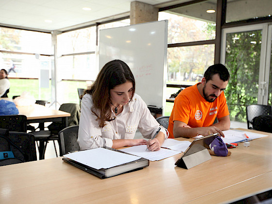 Dos estudiantes sentados frente a una mesa leyendo