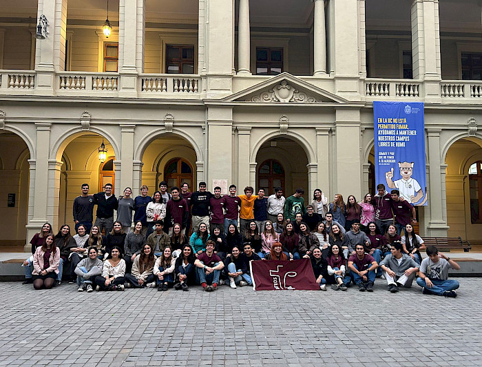 Grupo de 50 jóvenes de pie con una bandera en sus manos.