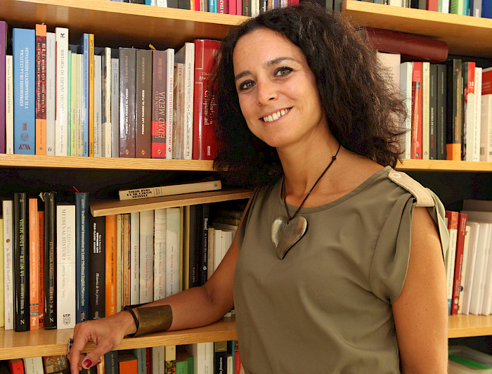 La académica Ximena Illanes posando junto a una biblioteca.