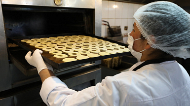 Una cocinera, dejando unos dulces en el horno.