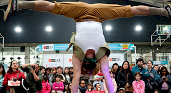 Una persona realizando una acrobacia en un escenario frente a un grupo de personas.