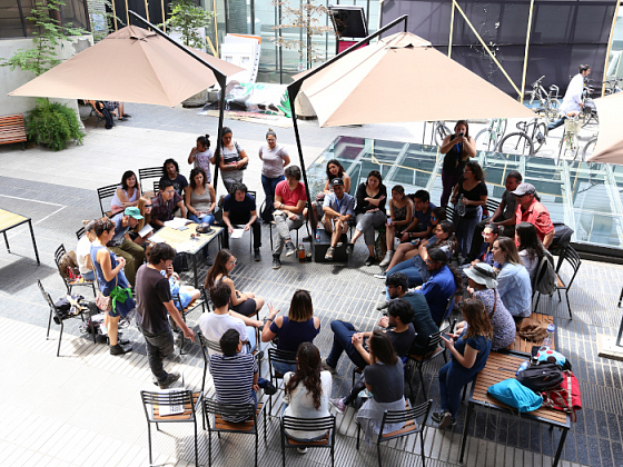 Grupo de alumnos sentados conversando reflexivamente en el patio de Medicina UC.